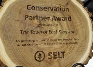 A piece of wood with the words "Conservation Partner Award to the Town of East Kingston" from SELT